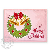 Vintage-inspired pink holiday card featuring a wreath with gold bells, berries, a red bow, and a "Merry Christmas" greeting.