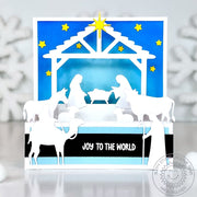 A 3D pop-up Christmas nativity scene card with white silhouettes under a blue sky, yellow stars & "Joy to the World" banner.