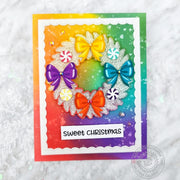Holiday Christmas Card featuring a white flocked wreath decorated with colorful bows & candy mints, and a rainbow background.