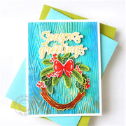 "Season's Greetings" Christmas Card featuring a holly holiday wreath with a red bow on a blue, woodgrain-embossed backdrop.