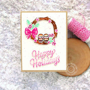 Pink handmade Christmas card featuring a grapevine wreath with birds, berries, & a pink bow with a "happy holidays" greeting.